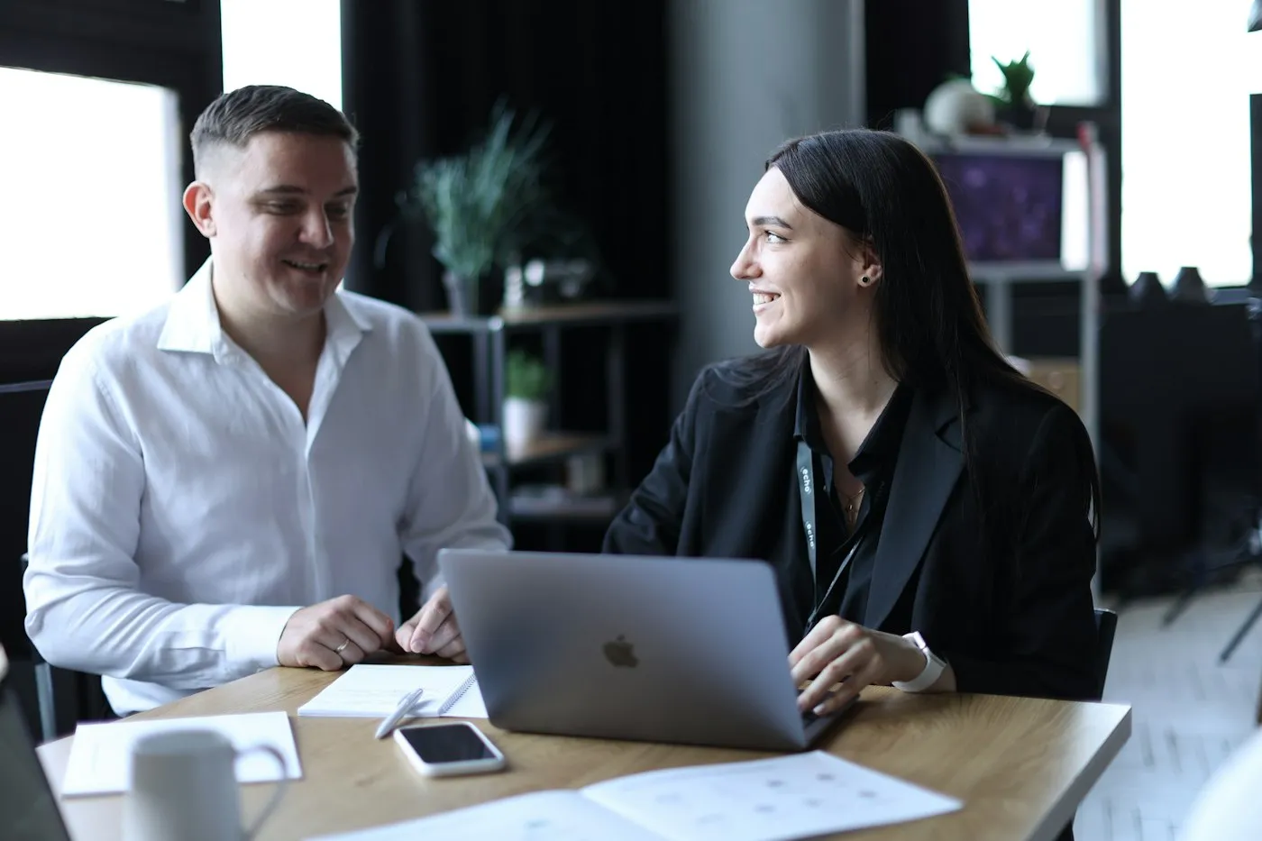 Two people talking through a project over a laptop at a table.