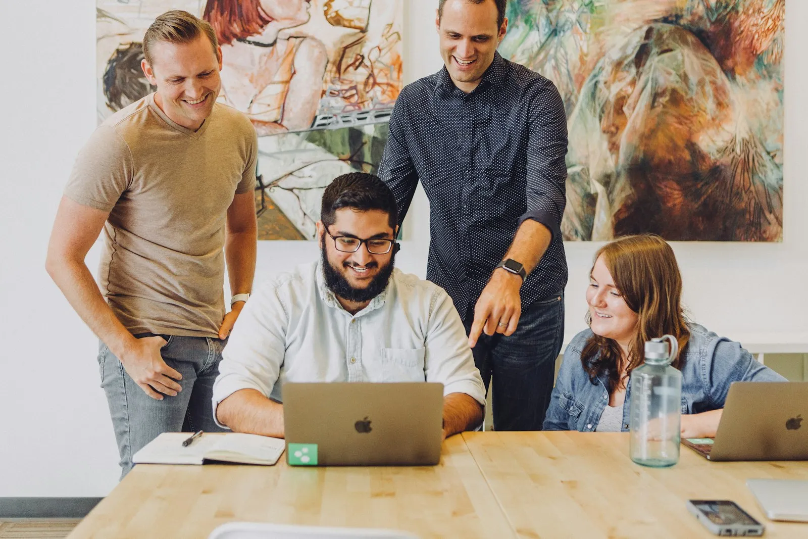 A team gathered around a laptop reviewing work together.
